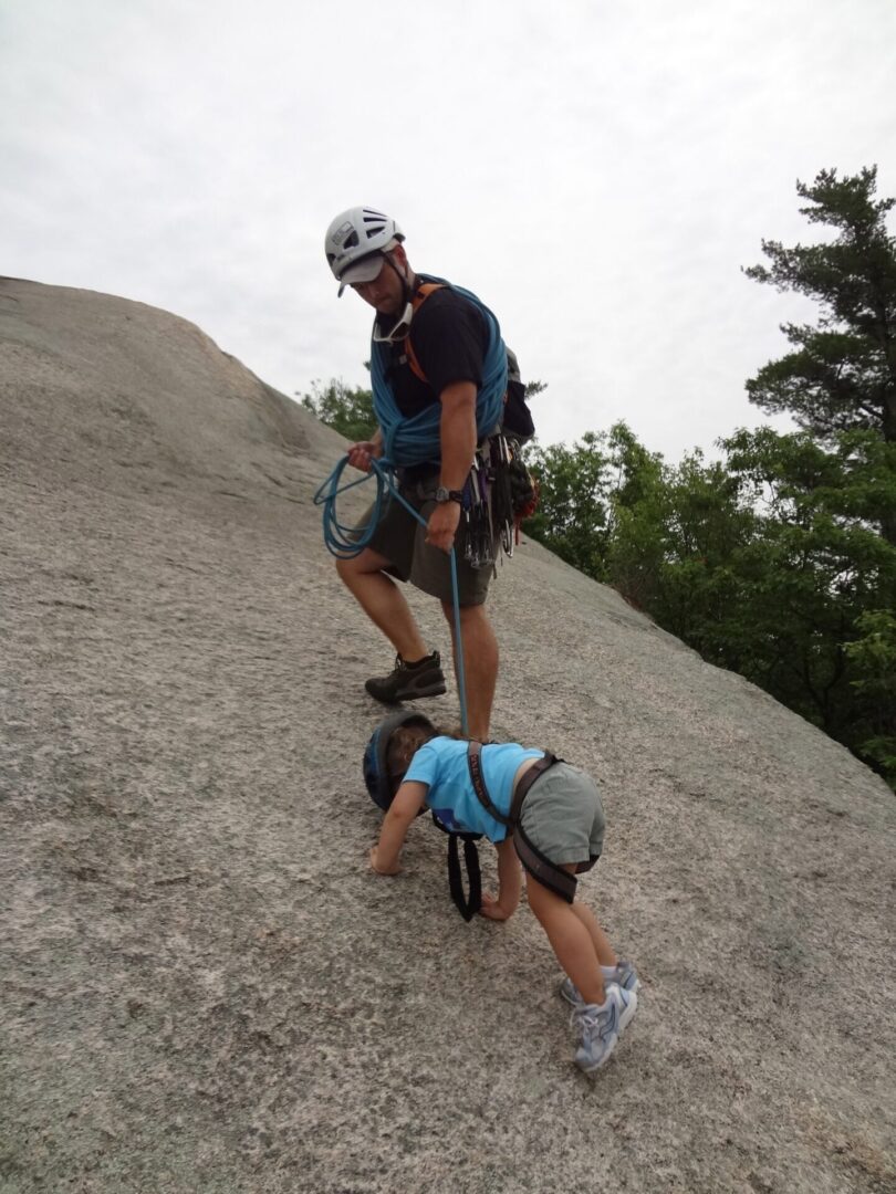 A man guiding a child and teaching him how to climb